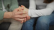 © Krakenimages.com - A man and woman emotionally holding hands indoors, showing support and love in a comfortable home setting.
