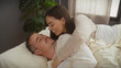 © Krakenimages.com - A woman tenderly embraces a smiling man as they relax together in a cozy bedroom setting, exemplifying a loving couple's intimate moment at home.