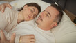 © Krakenimages.com - A contented couple enjoys a serene moment together in a cozy bedroom setting, exuding domestic bliss and comfort.