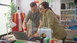 © Krakenimages.com - In a bright tailor shop, a focused man and woman team design clothes together with a laptop and sewing machine.