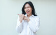 © M Alfan Setyawan - studio shot of excited asian young business woman pointing to side empty space with her thumbs look at camera flirting blink eye wearing white formal suit shirt isolated on white background