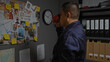 © Krakenimages.com - Hispanic man drinking coffee in a police station office with investigation evidence board
