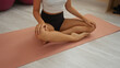 © Krakenimages.com - Young woman practicing yoga on a pink mat, indoors at a gym center, focusing on her hands and legs during meditation