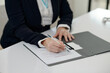 © DragonImages - Close-up of social worker filling document at table in office