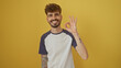 © Krakenimages.com - Handsome young man with beard making okay gesture against yellow background