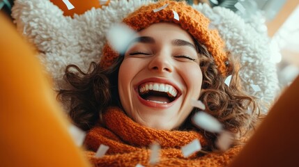 a cheerful woman laughing joyously, surrounded by confetti and dressed in warm, orange winter attire