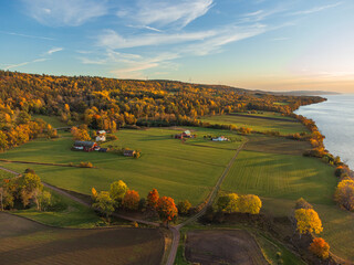 Wall Mural - Autumn rural landscape in Sweden near Gränna, from above with vibrant colors and large open fields, at sunset. Orange, yellow and green trees, green open fields, red houses.