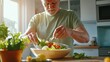 © ibooM - A senior man enjoys preparing a fresh salad in a bright kitchen.