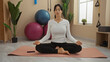 © Krakenimages.com - Young hispanic woman meditating on yoga mat in indoor gym surrounded by fitness equipment like exercise balls and trx bands, creating a peaceful atmosphere for wellness practice