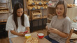 © Krakenimages.com - Mother and daughter sitting together in a bakery cafÃ© using smartphones while enjoying their coffee and pastries displaying a mix of technology and family bonding in an indoor setting