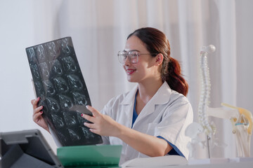 Analyzing x-ray image. beautiful thoughtful doctor looking at x-ray diagnosis while sitting near computed tomography scanner.