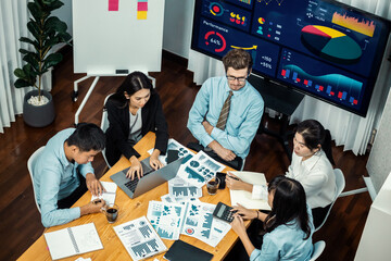 Wide top view of diverse group of business analyst team analyzing financial data report paper on meeting table. Chart and graph dashboard by business intelligence analysis. Meticulous