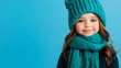 © Nemanja - Cheerful girl child wearing cozy scarf for winter warmth, kid styled in knitted fashion accessory with young female portrait smile in studio, copy space, blue