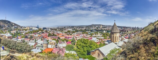 Panoramic daytime view over the city of Tbilisi, Georgia, with colorful rooftops and landmarks