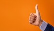 © MAGIC  FHOTOS - A hand with a raised finger signaling approval against a bright orange background, symbolizing a positive affirmation
