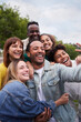 © CarlosBarquero - Vertical. Cheerful group of friends taking smiling selfie. Group of young people having fun together outdoors at park in the city enjoying travel in vacation holidays.