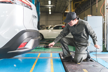 車検の完成検査をする自動車整備士・検査員の男性メカニック
