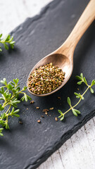 wooden spoon filled with brown seeds green thyme