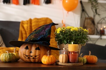 Wall Mural - Burning candles, flowers and pumpkins on table in room decorated for Halloween