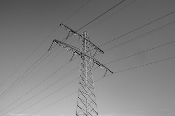 Black and white shot of an electricity pylon with its cables with the sky in the background