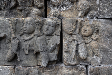 Wall with old historic stone statues in Borobudur Temple in Indonesia