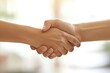 © Putt_Sanplee - A close-up of a handshake between two professionals, emphasizing their agreement and collaboration. The background features a blurred office environment with natural light streaming in