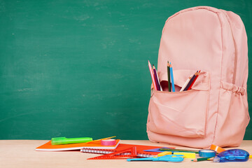 Pink backpack and colored pencils on desk background