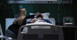 © ABCreative - Exhausted tired young woman enters the hospital ward of his husband sits and supports while man in coma .