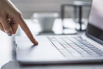 Picture captures a woman's hands typing on a stylish laptop keyboard, with the office surroundings appearing blurred in the background