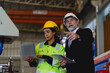 © ronnachaipark - Two people are looking at a laptop, one of them is wearing a yellow jacket. Scene is serious and focused to machine controller board in factory.