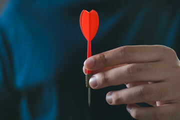 A close-up of a hand holding a red dart, symbolizing precision and focus in a game or sport.