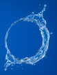 © Tark - An image of a ring of clear water splashing upward against a deep blue background. The ring should be incomplete, with the water droplets captured in mid-air, creating a dynamic Generative AI