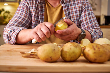 man in the kitchen peeling potatoes