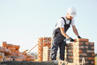 © Serhii - Construction worker man in work clothes and a construction helmet. Portrait of positive male builder in hardhat working at construction site