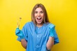 © luismolinero - Dentist caucasian woman holding tools isolated on yellow background celebrating a victory in winner position