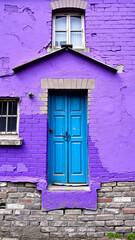 Poster - vivid blue door against a purple brick wall