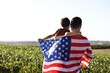© New Africa - Father and son with flag of USA outdoors. back view. Space for text