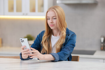 Sticker - Beautiful woman using smartphone at white table in kitchen