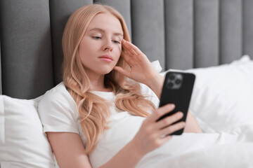 Sticker - Beautiful woman looking at smartphone in bed