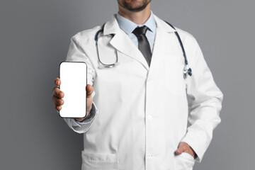 Canvas Print - Doctor showing smartphone with blank screen on grey background, closeup. Mockup for design