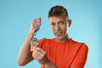 Wall Mural - Handsome winner with bronze medal on light blue background