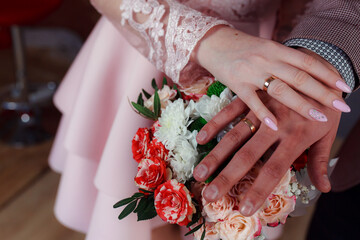 Wedding bouquet in the hands of the bride at the ceremony. Touching the hands of the bride and groom. Wedding jewelry. Wedding rings. The tenderness and beauty of the wedding ceremony.