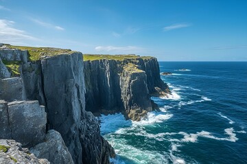 Incredible coastline where sheer rocky cliffs tower above the crashing waves of the deep blue ocean. Bright blue sky.