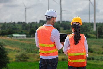 Fototapete - Team engineer wearing safety uniform holding laptop discussed plan about renewable energy at station energy power wind. technology protect environment reduce global warming problems.