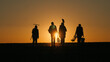 © StockMediaSeller - A family of farmers with working equipment walks through a field at sunset. End of the working day