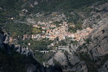 Italian village on hill side surrounded by trees and rocky mountains, sunny day, Castelmezzano, Italy