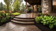 © Cheewynn - Elegant stamped concrete patio leading to a rustic home entrance, designed to resemble natural flagstone, surrounded by lush greenery