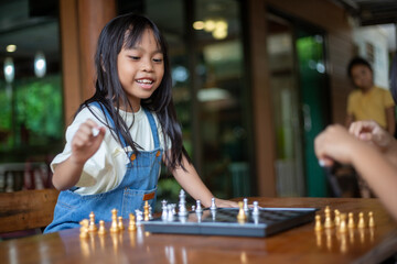 A young girl is playing a game of chess with another child