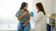 © AntonioDiaz - Latin female patient is getting vaccinated by a doctor wearing gloves in a medical office