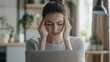 © Ganesha88 - Woman experiencing a headache while working on laptop, stressed and frustrated